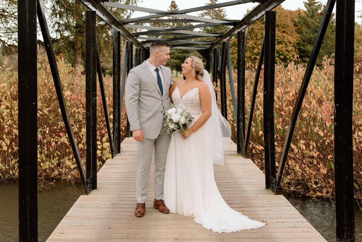 bride and groom on a bridge, surrounded by fall colours