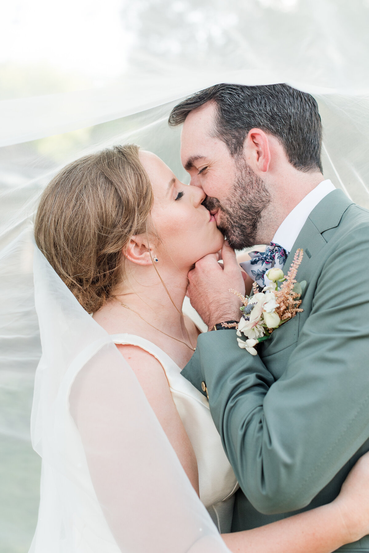 couple kissing on wedding day sage green suit