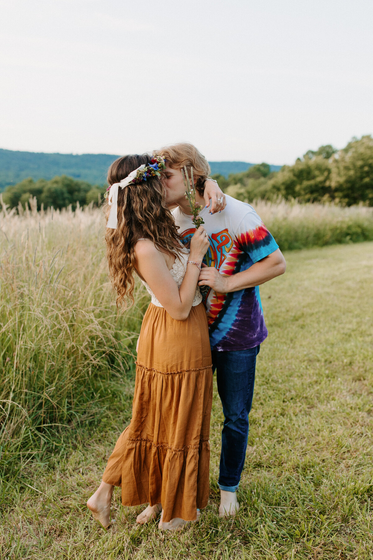 couple kissing while standing in a grassy field