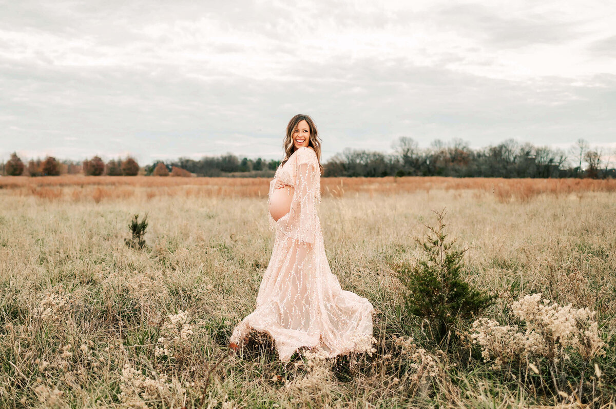 pregnant couple cuddling in field laughing in field captured bySpringfield MO maternity photographer