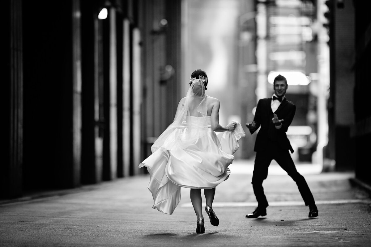 Black and white picture of bride running to her groom in a dark alley in downtown Chicago
