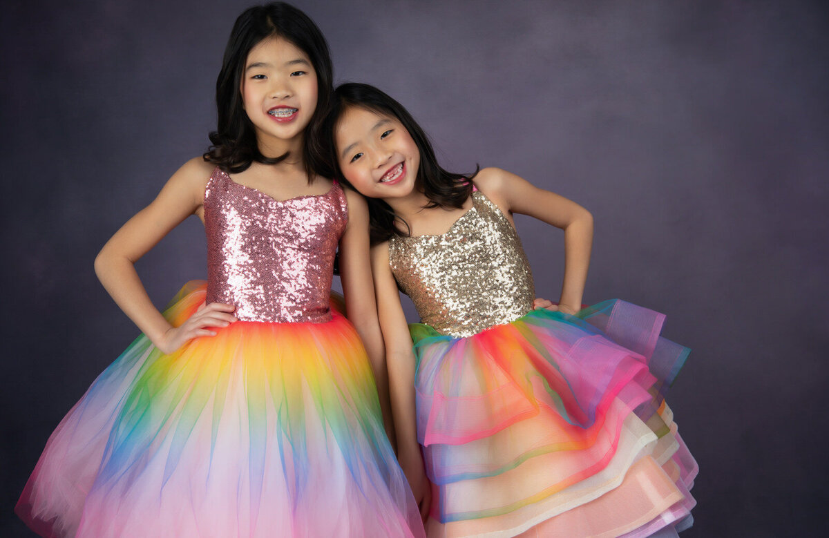 sisters-wearing-rainbow-dresses-posing-in-studio-arlington
