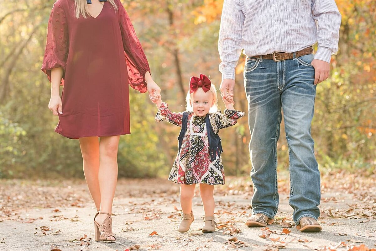 picture of little girl walking with her parents in the fall leaves at glenn hilton park
