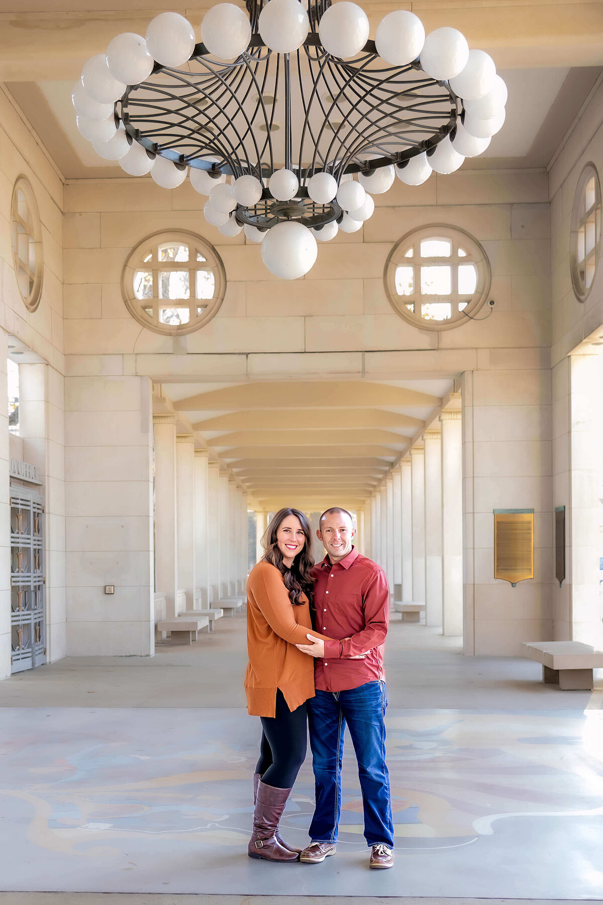 a couple hugging under a big chandelier under a covered walkway outdoors