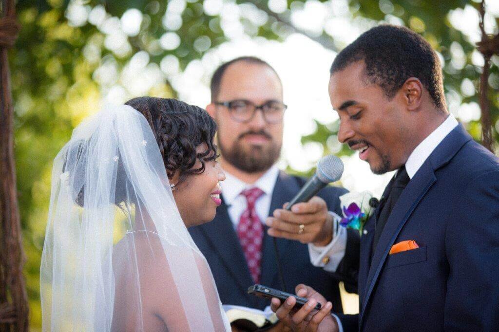 A close up photo by philippe studio pro of a groom saying his vows to the bride with a microphone in front of him.