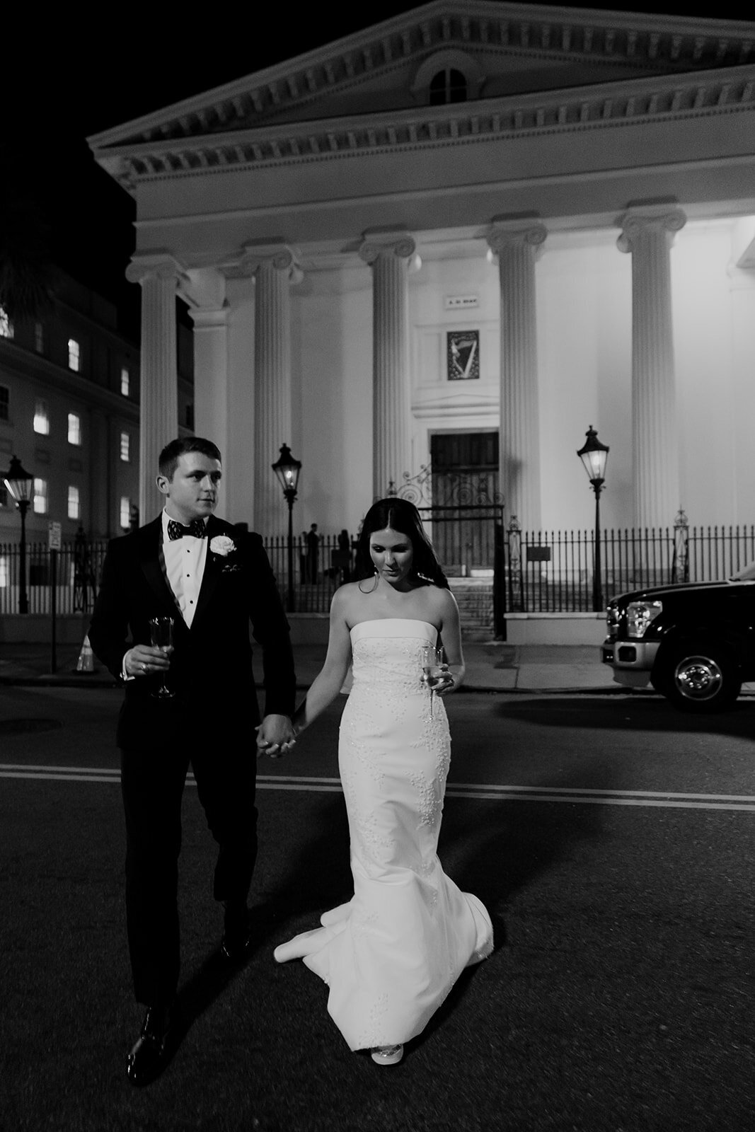 Charleston ewdding photographers photographed couple walking across street at night. Hibernian Hall Charleston in background