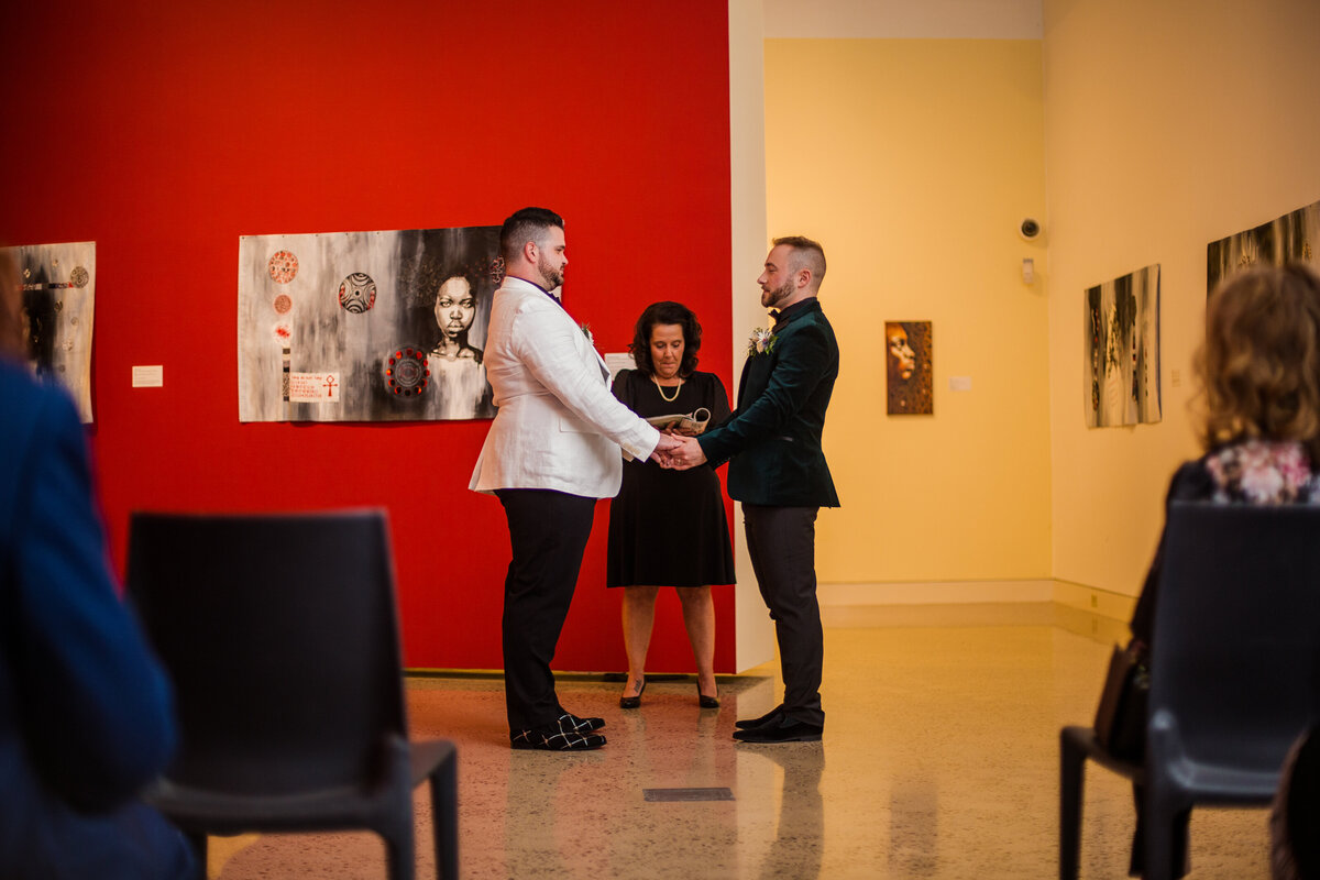 Grooms exchange vows in the gallery space of the Erie Art Museum