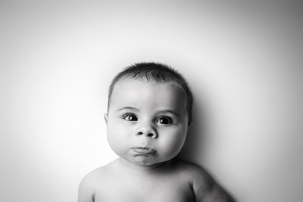 Black and white in home studio newborn portrait of awake baby with pouty lip and bubbles in Jacksonville, FL.