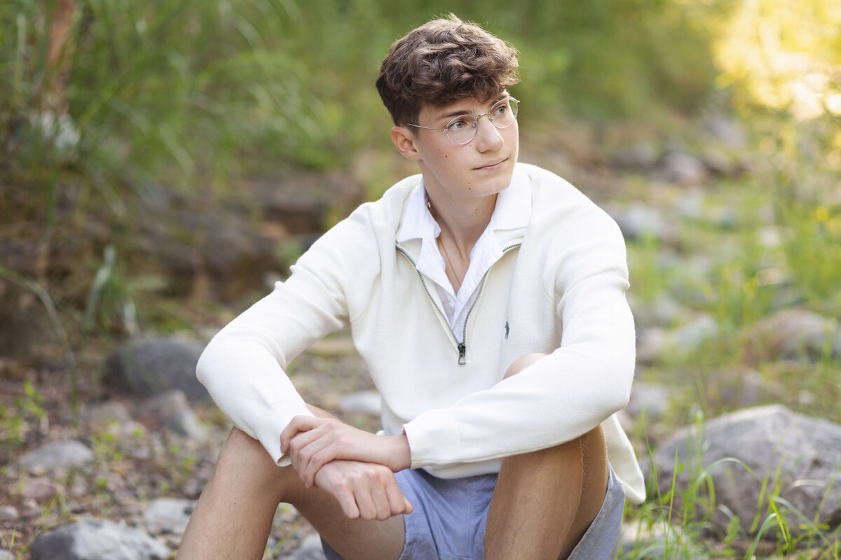 boy sitting on rocks looking to the side