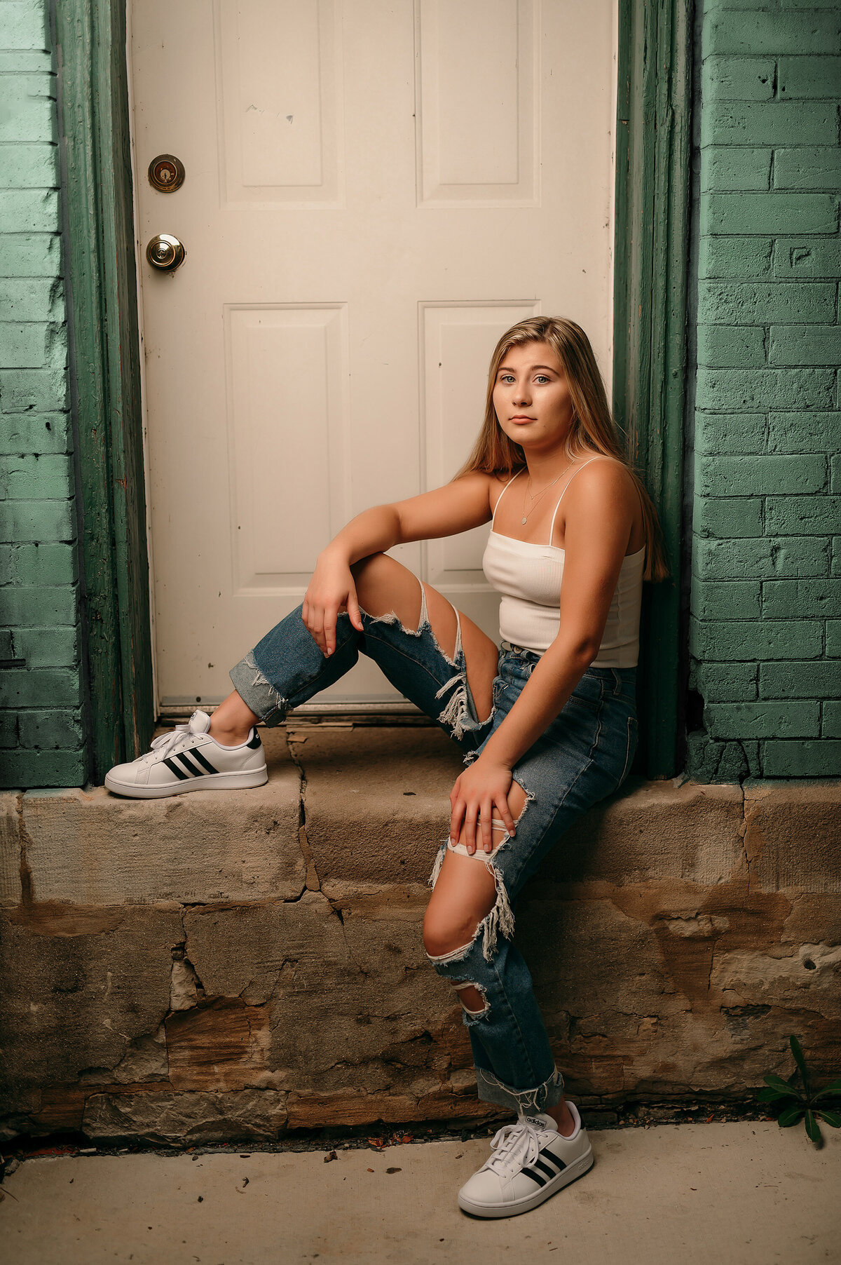 A senior student from Waukesha North High School poses in ripped jeans on a deteriorating concrete wall in Milwaukee's Third Ward.
