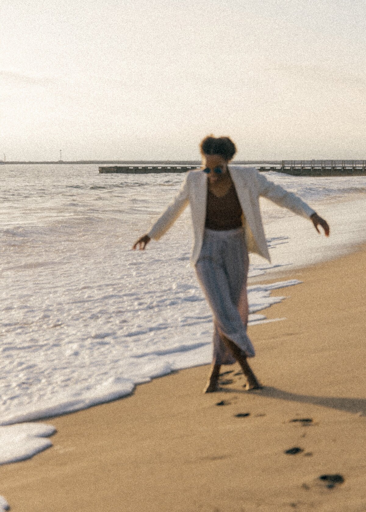 Photo of a woman at the beach with a sun setting