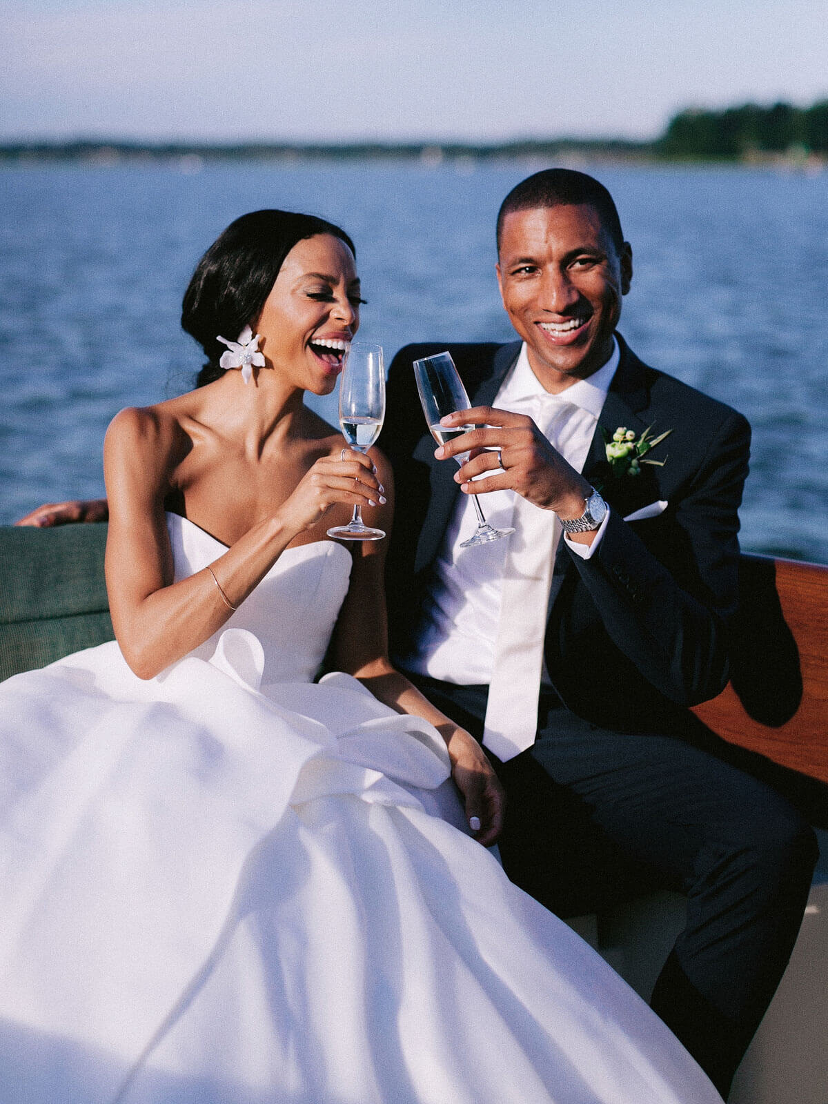 The bride and groom are drinking champagne on a yacht in Montage at Palmetto Bluff. Destination wedding image by Jenny Fu Studio