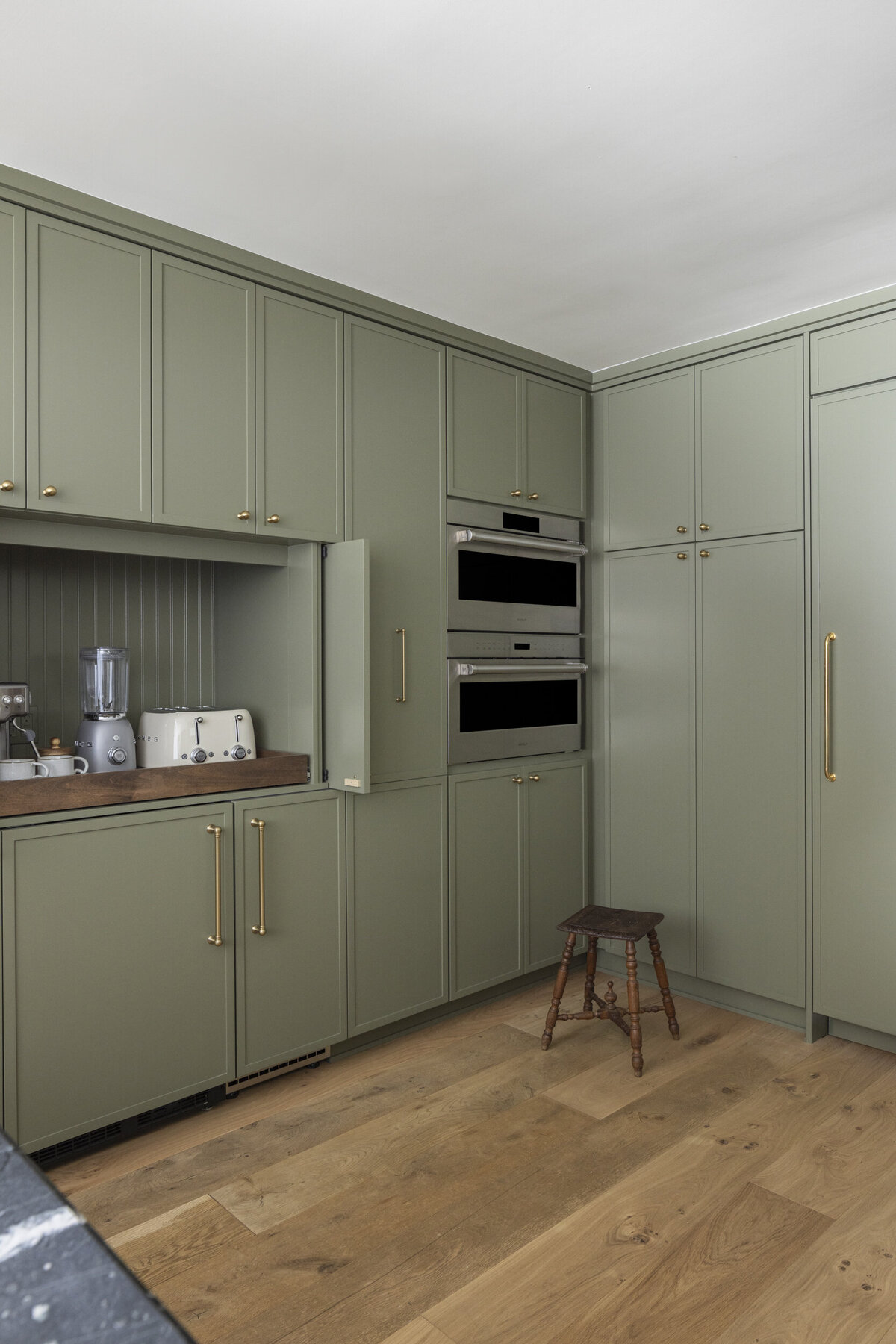green skinny shaker kitchen cabinets with  a breakfast bar. Wolf steam oven and drawer microwave