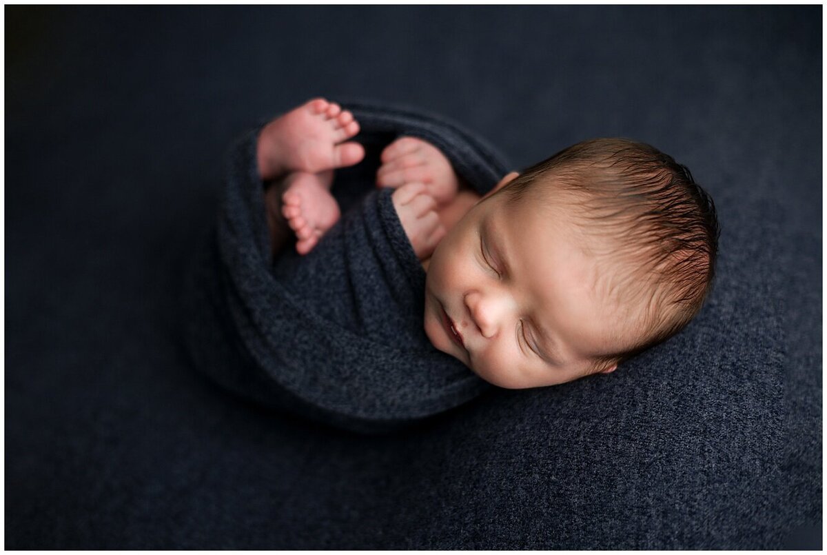 Newborn baby boy asleep in navy blue