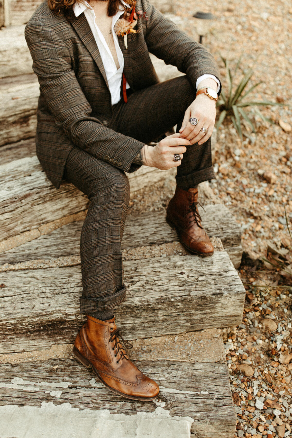 Groom in plaid suit and boots sitting on steps