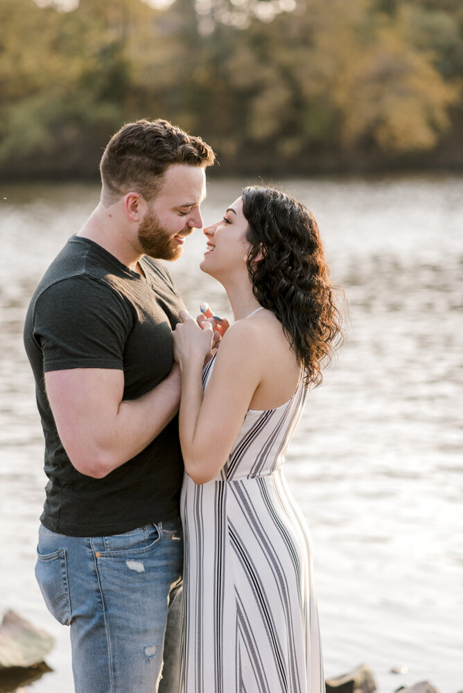 outdoor portrait of engaged couple kissing by the water