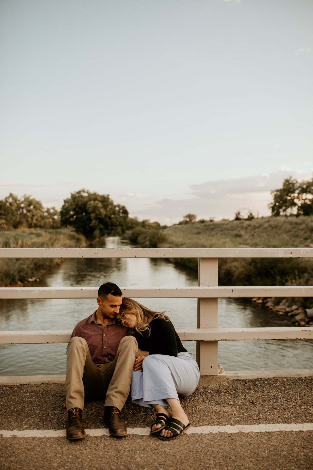 engaged couple sitting on a bike bridge over the arroyo on Albuquerque