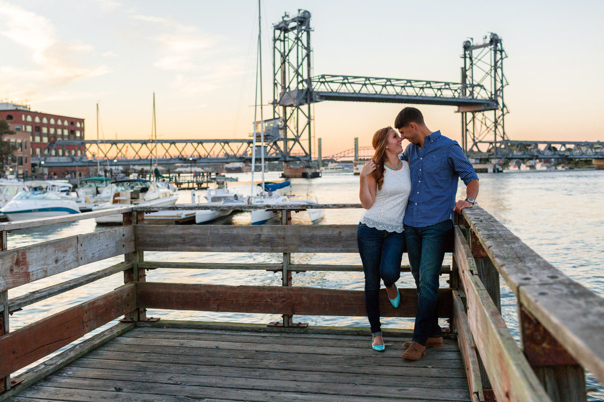 The Memorial Bridge in Portsmouth NH sits behind the couple out on the docks