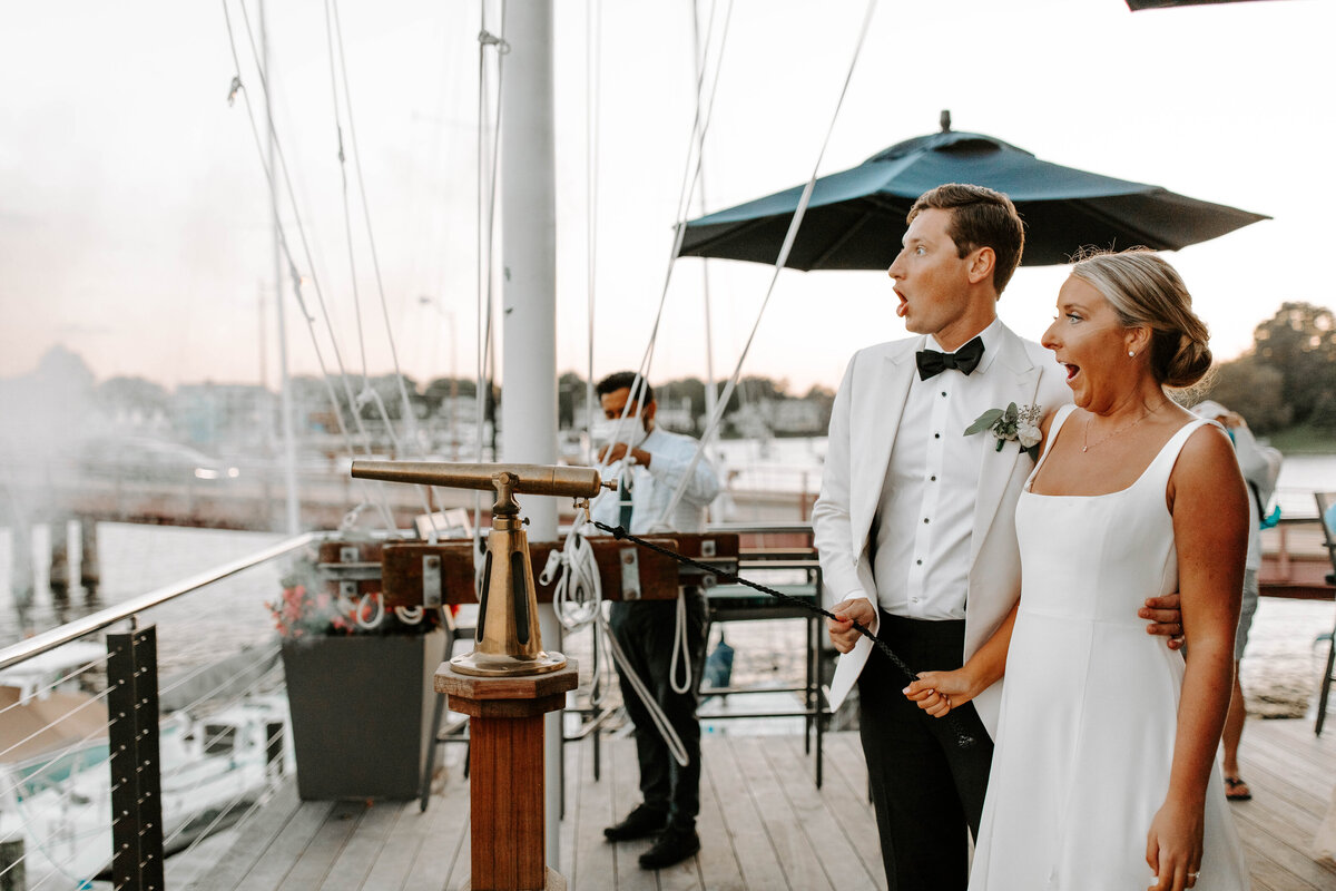 A bride and groom pull a cannon at the Annapolis Yacht Club, the couple is making a surprised face from the loud noise.