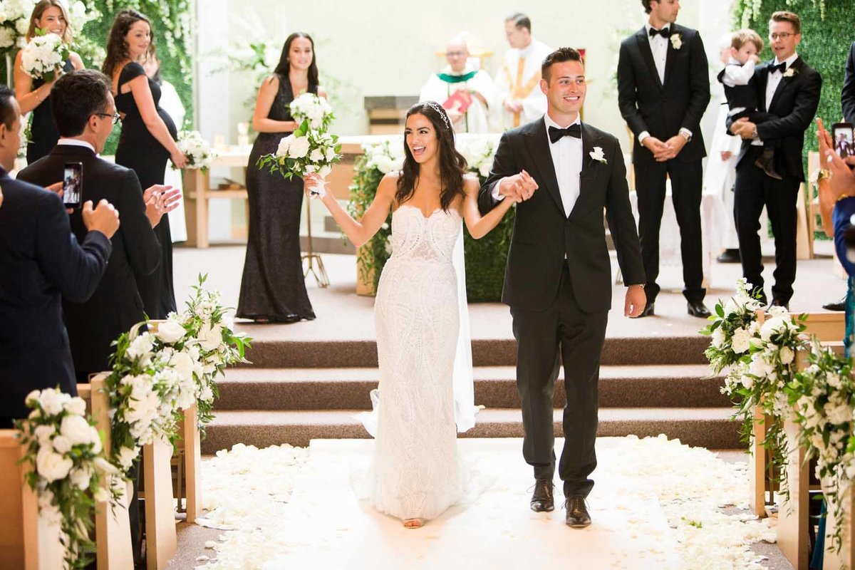 Bride and Groom walking down aisle with white rose petals