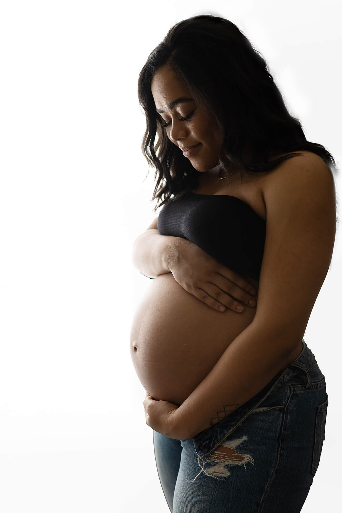 Pregnant woman posed hugging her belly.