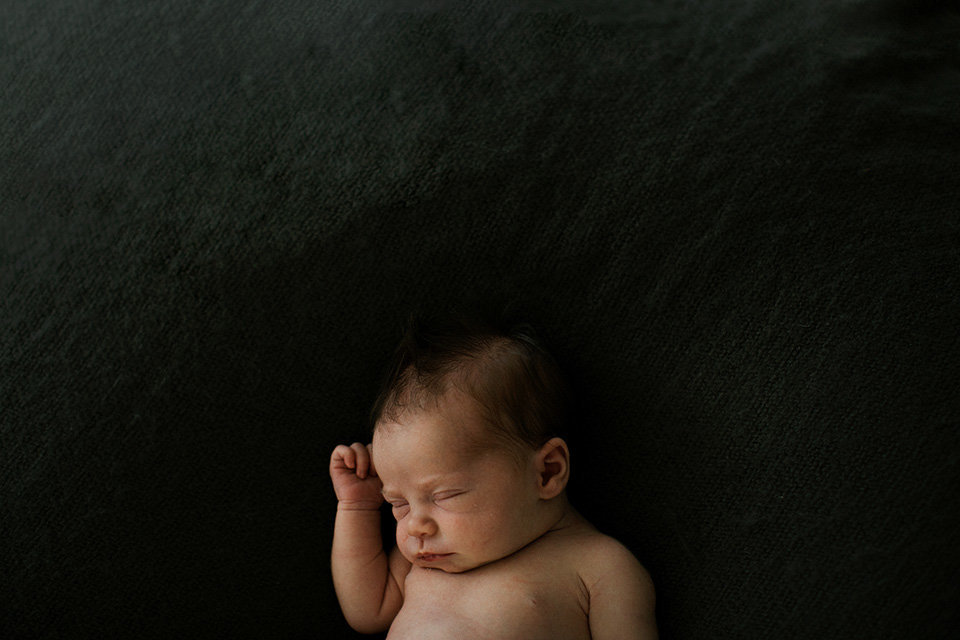 Baby girl on a dark blanket in Elle Baker Photography's newborn studio
