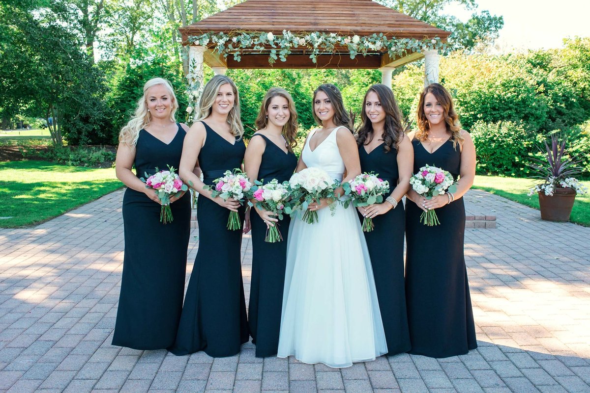 Bride and bridesmaids posing in front of outdoor reception area at Stonebridge Country Club