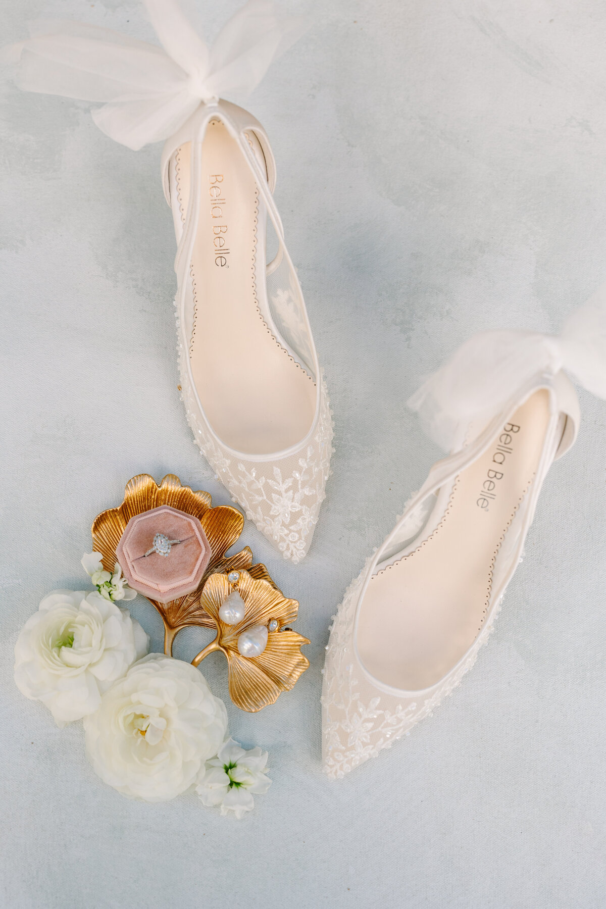 flat lay image of bride shoes, jewelry, and flowers.