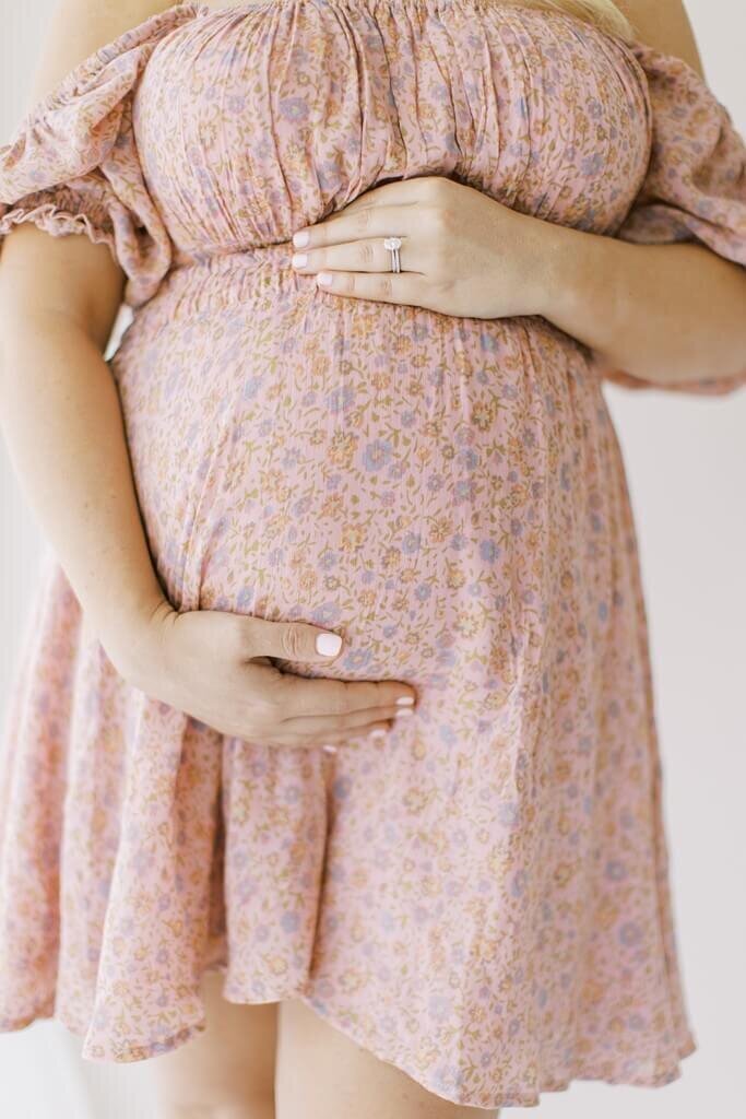 Close up of baby bump in a floral maternity dress.