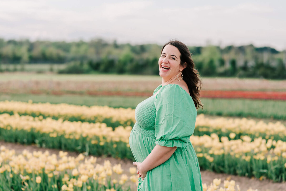 A woman holding her belly and laughing at her motherhood session, taken by a northern VA maternity photographer