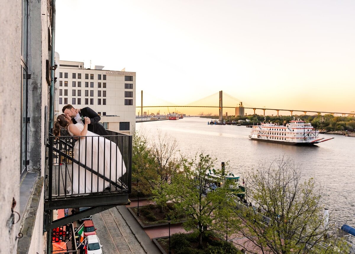 Groom kissing bride on balcony Vic's on the River Savannah Georgia