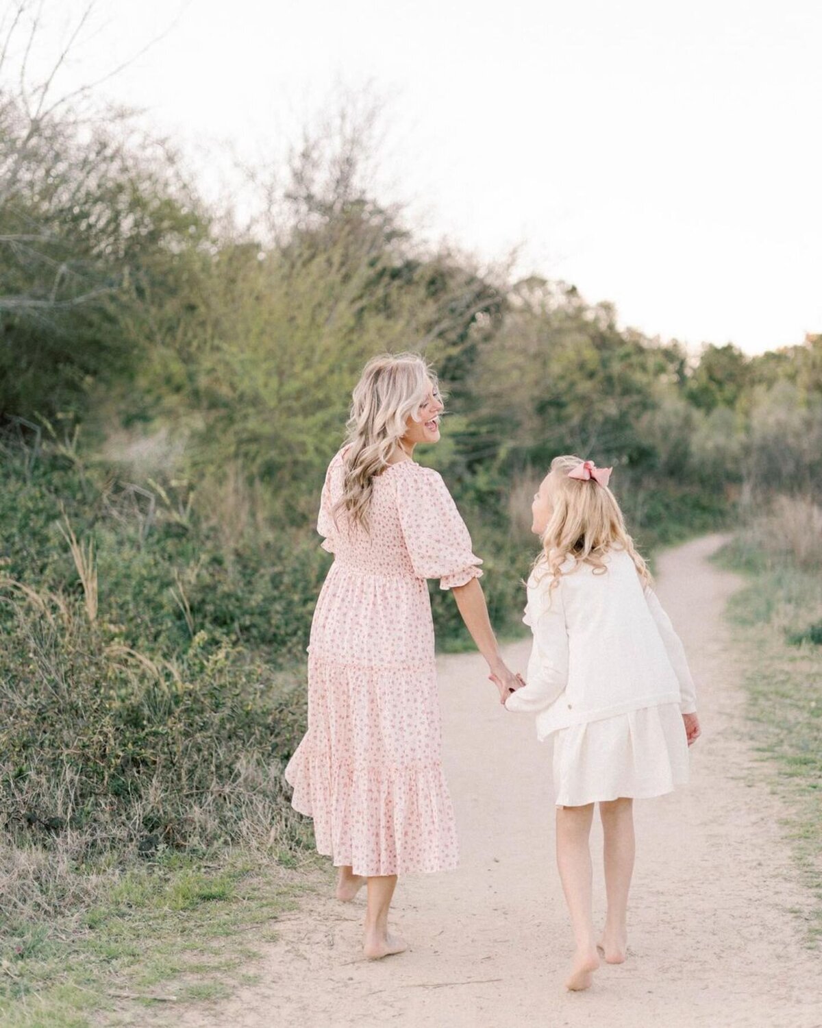 Mother runs on sand path holding daughters hand