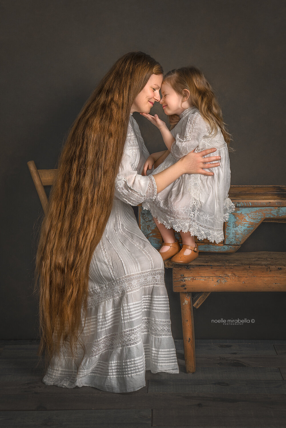 Mother and daughter sitting at a table engaged in a warm embrace.