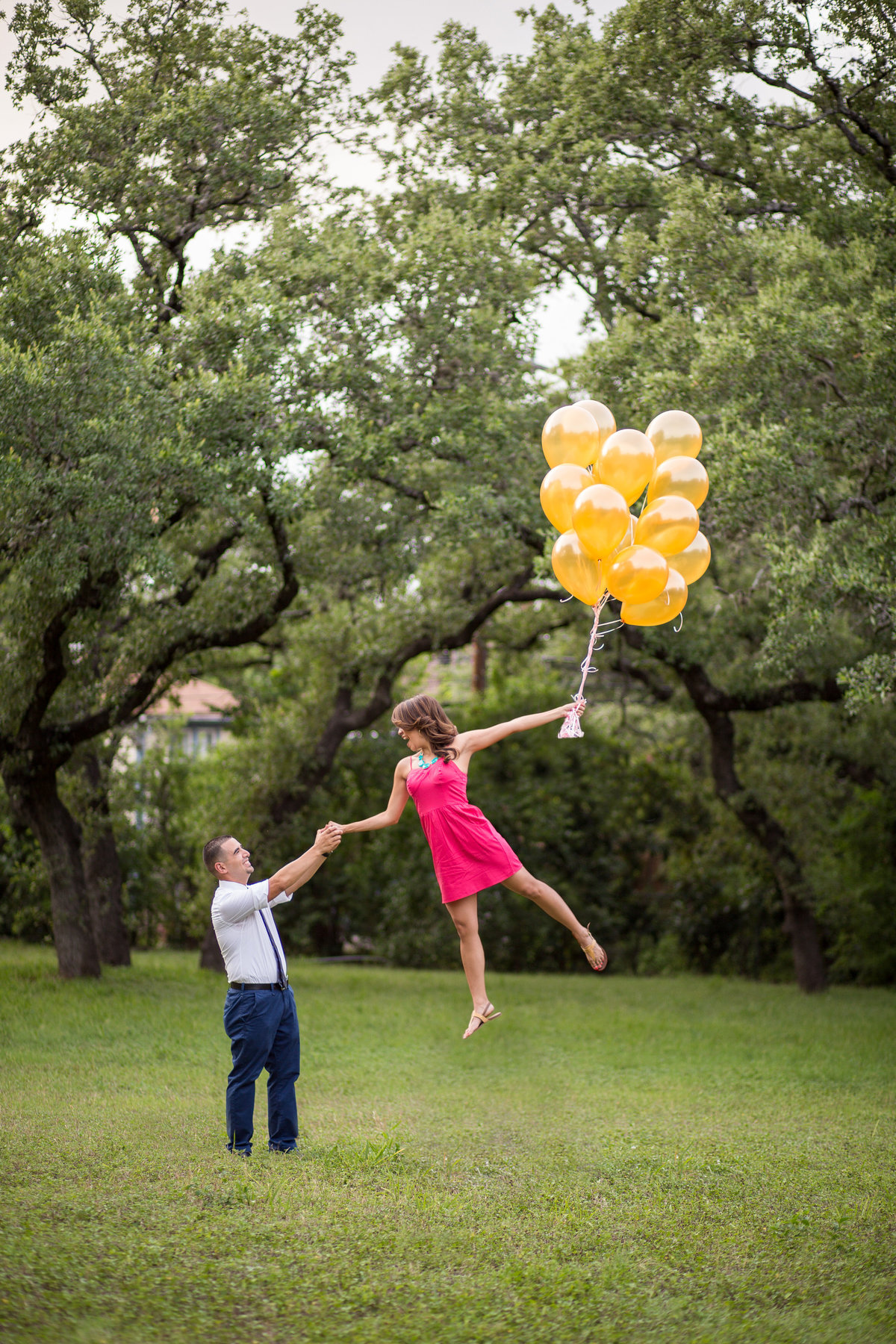Engaged Woman holding her fiancé hand while she floats away holding balloons