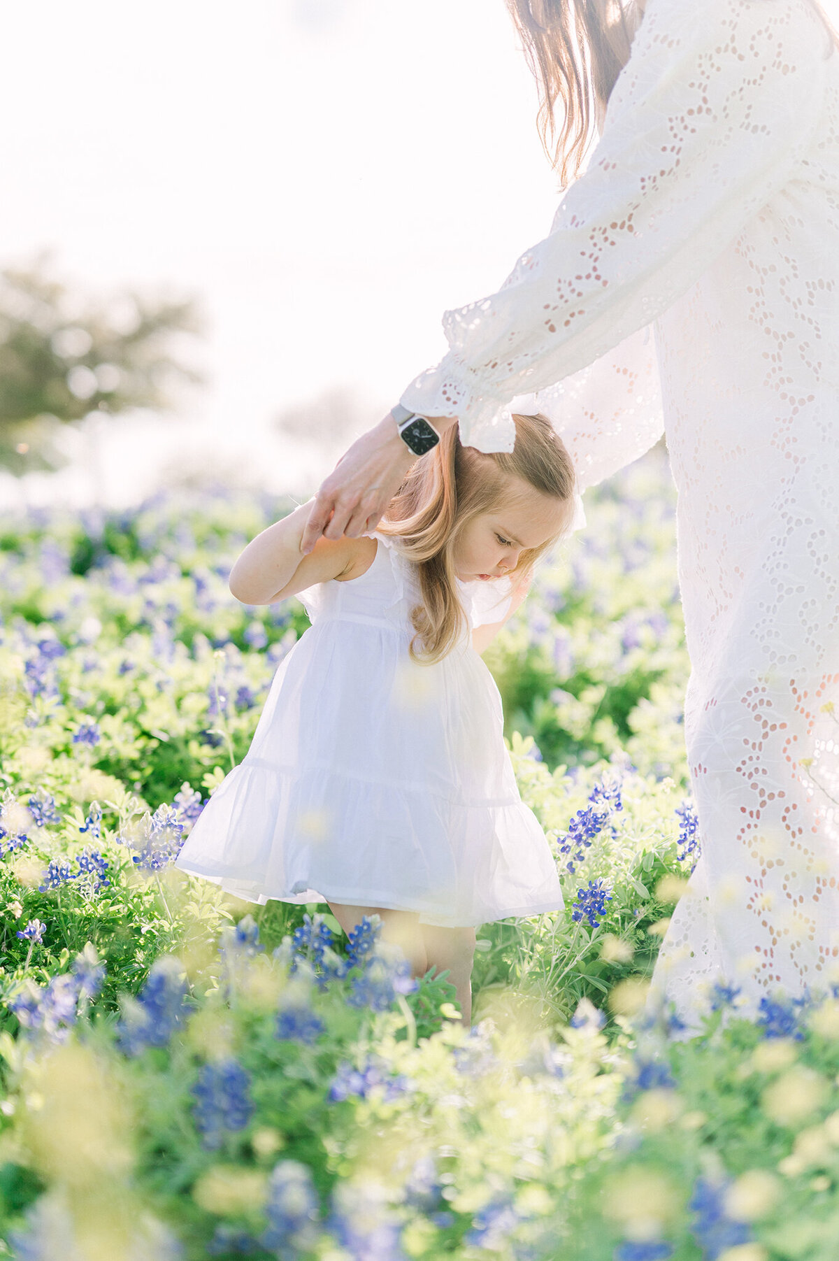 Mother dancing with daughter in a field of bluebonnets.