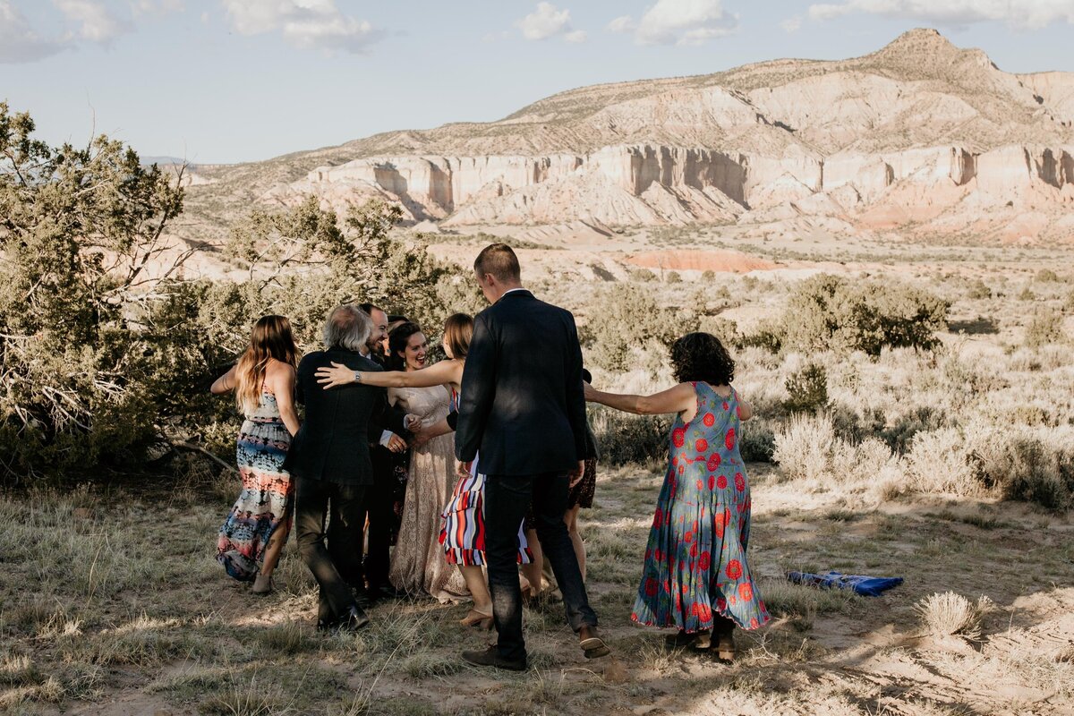 guests running up to couple to hug in the desert