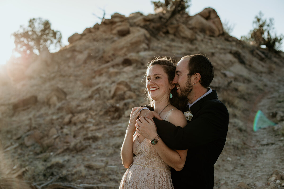 groom whispering to bride in the desert
