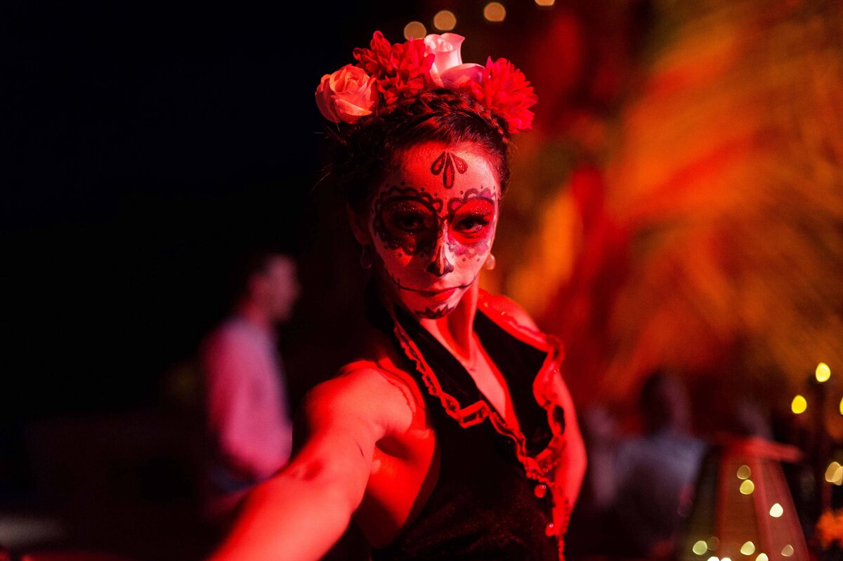 A professional dancer wearing day of the dead face paint and costume stares into the camera while offering a special cultural experience.