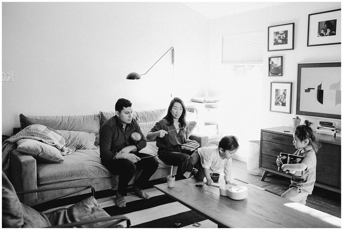 Man and woman watching kids play in living room at family photo session in Austin by Amber Vickey Photography