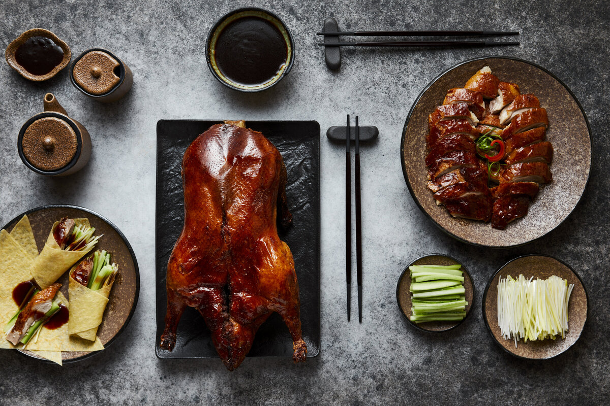 A roasted duck with various side dishes on the table next to it.