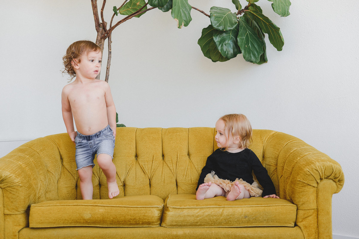 2 children sitting on a mustard couch