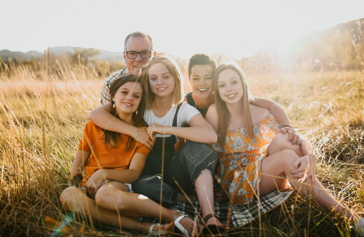 naturally posed family sits together in field for lifestyle photoshoot