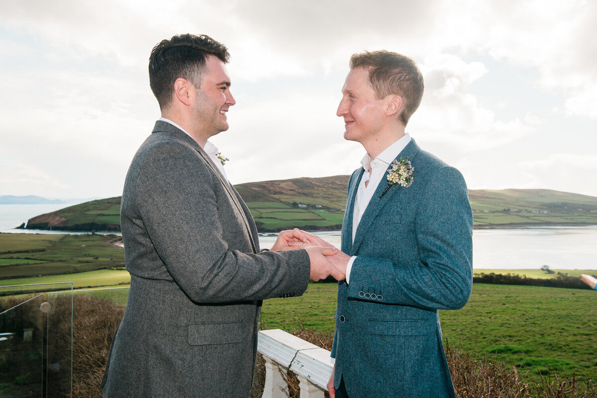 Gay grooms exchanging rings on the terrace of Pax House in Dingle