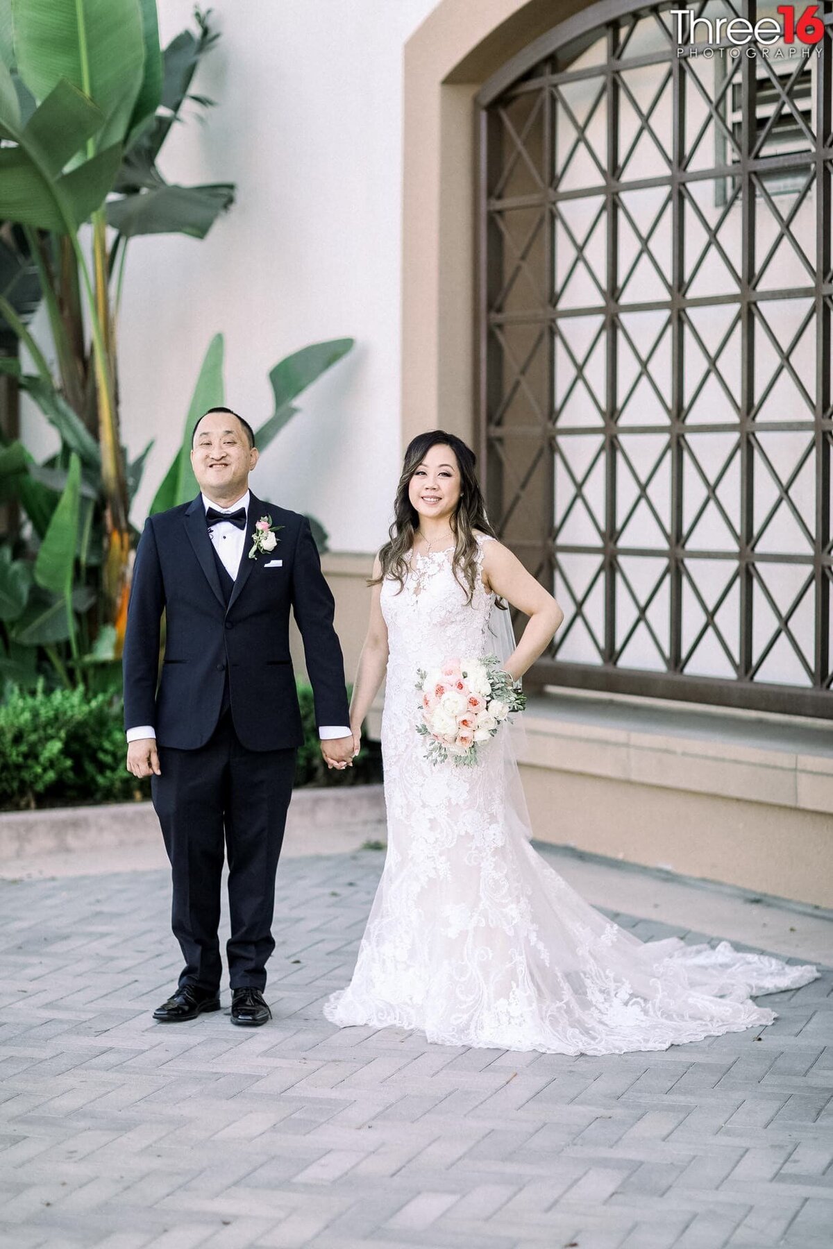 Bride and Groom stand outside the church holding hands while posing for photos