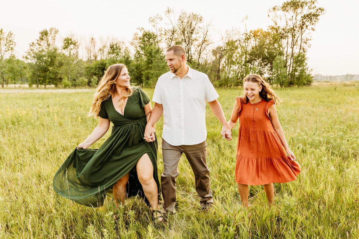 beautiful family walking and laughing in a field near oshkosh together
