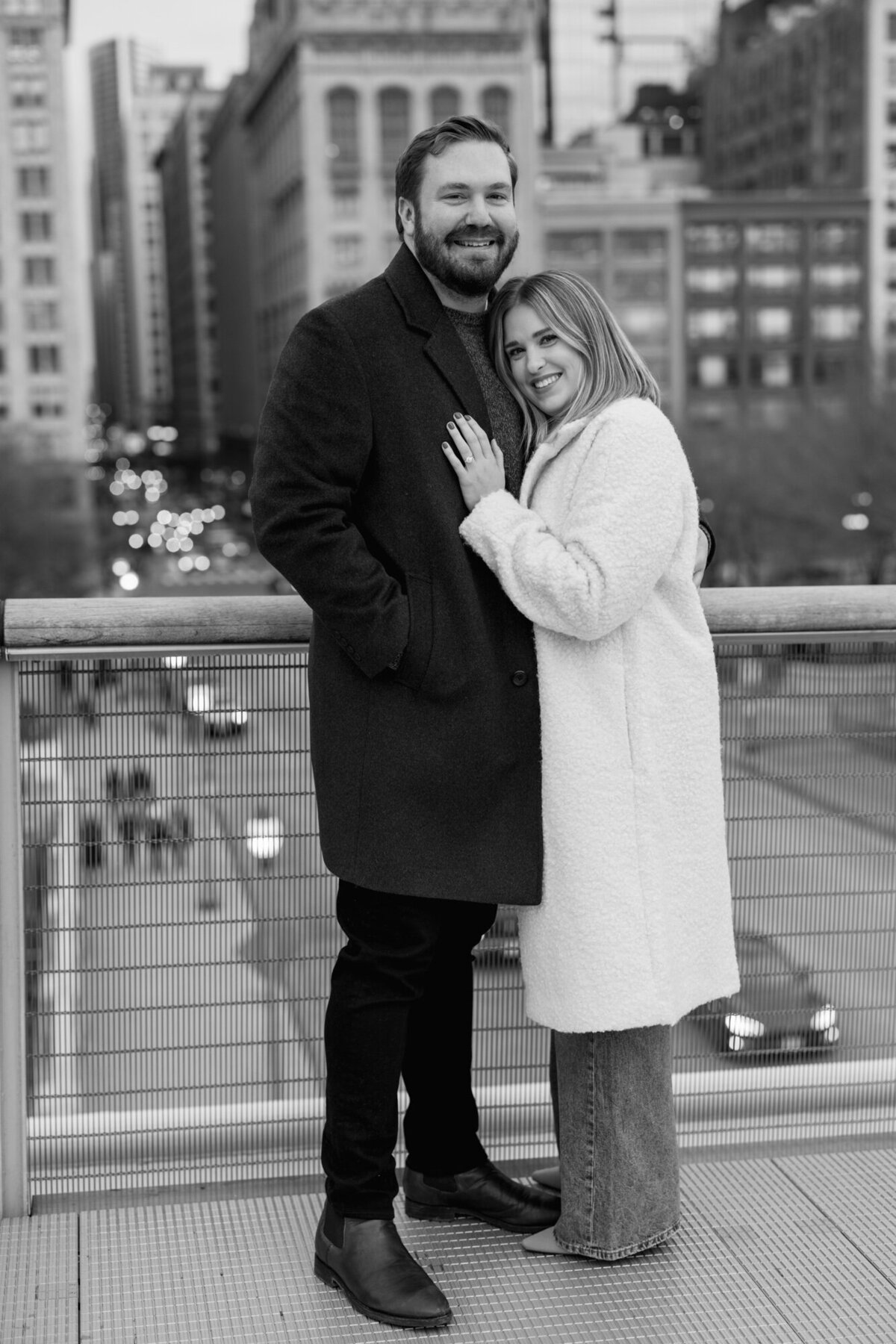 A couple smiles at the camera as they pose for an engagement photo during the winter in downtown Chicago