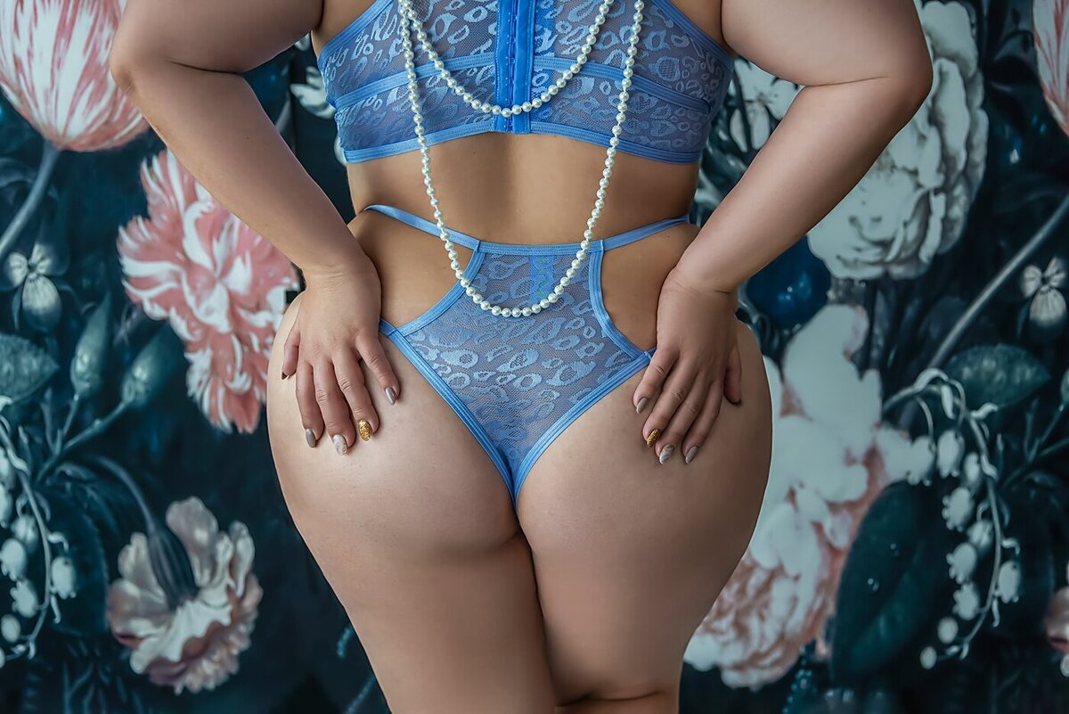 A woman in blue lingerie poses during her boudoir photoshoot.