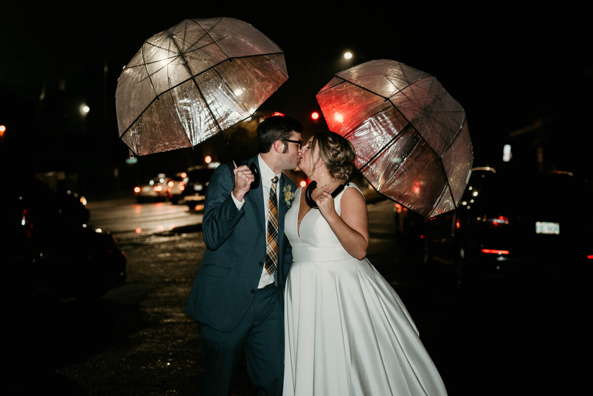 Bride and groom kiss under umbrellas