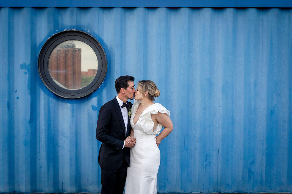 Bride and Groom posing in front of Blue Shipping container at Trinity Buoy Wharf