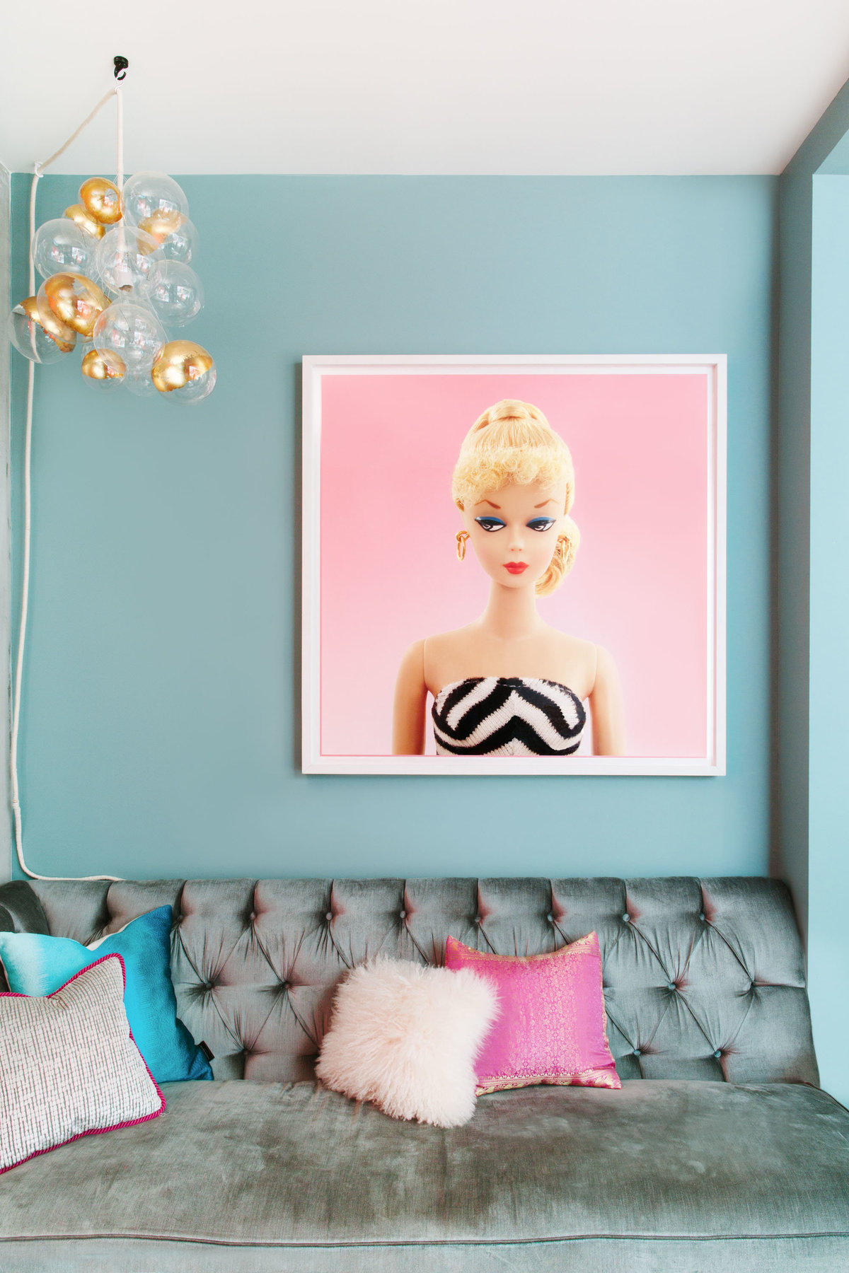 Vintage Barbie art, bubble light, and tufted sofa